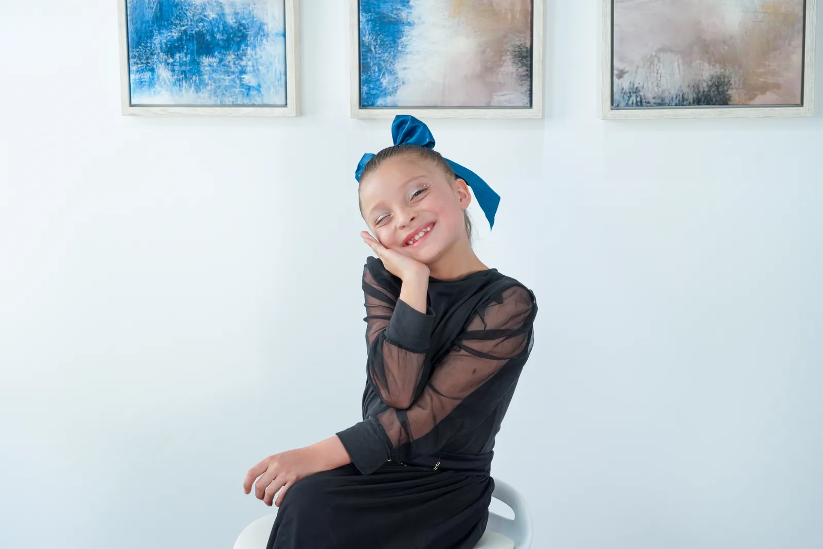 A girl smiles with her hand on her cheek during a portrait session.