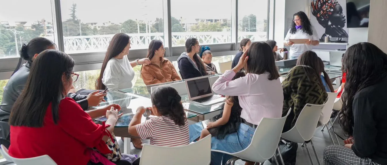 Mujeres y niñas de distintas edades trabajan alrededor de una mesa durante un encuentro de la fundación en Bogotá.
