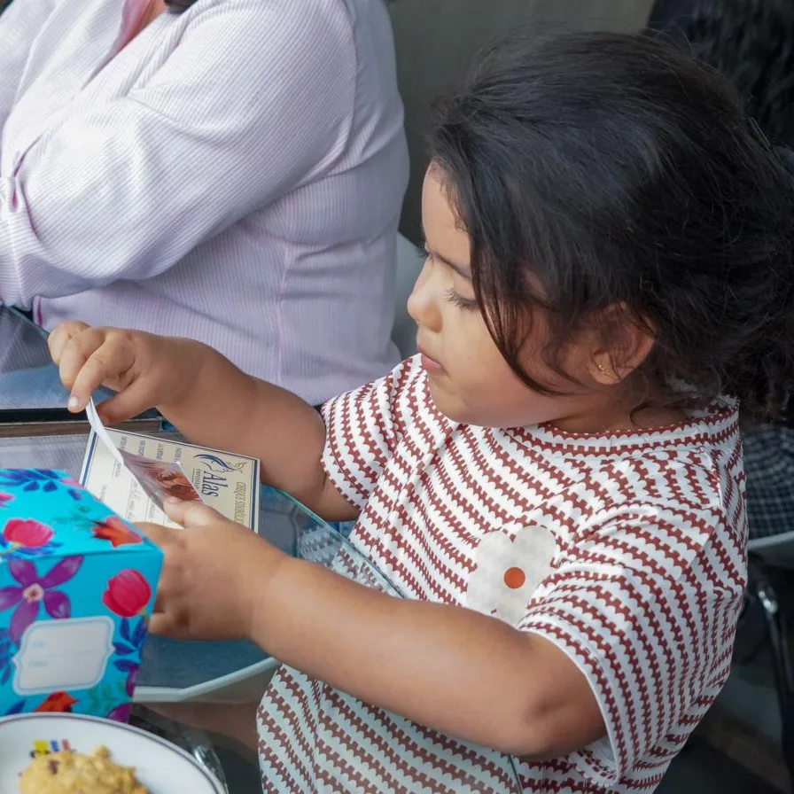 Una niña trabaja con sus materiales sobre la mesa, concentrada en la actividad.